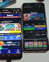 Two smartphones are displayed on a white surface, both showing gambling websites with colorful graphics, text, and various options for logging in and accessing games. The screens are bright and filled with promotional content related to casino and slot games.