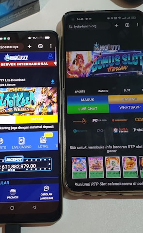 Two smartphones are displayed on a white surface, both showing gambling websites with colorful graphics, text, and various options for logging in and accessing games. The screens are bright and filled with promotional content related to casino and slot games.